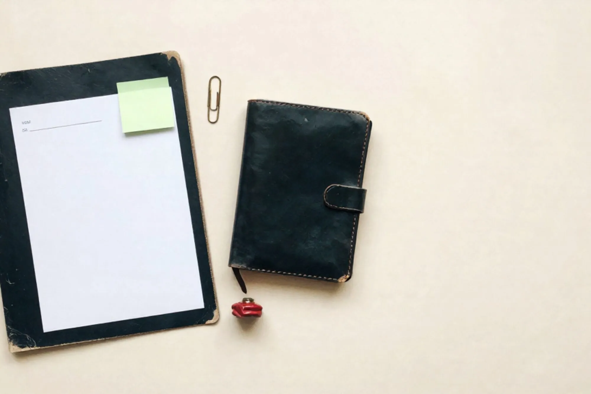 Manila folder with typewritten index card, chartreuse sticky note, brass paperclip, leather notebook, red wax seal on ivory paper.