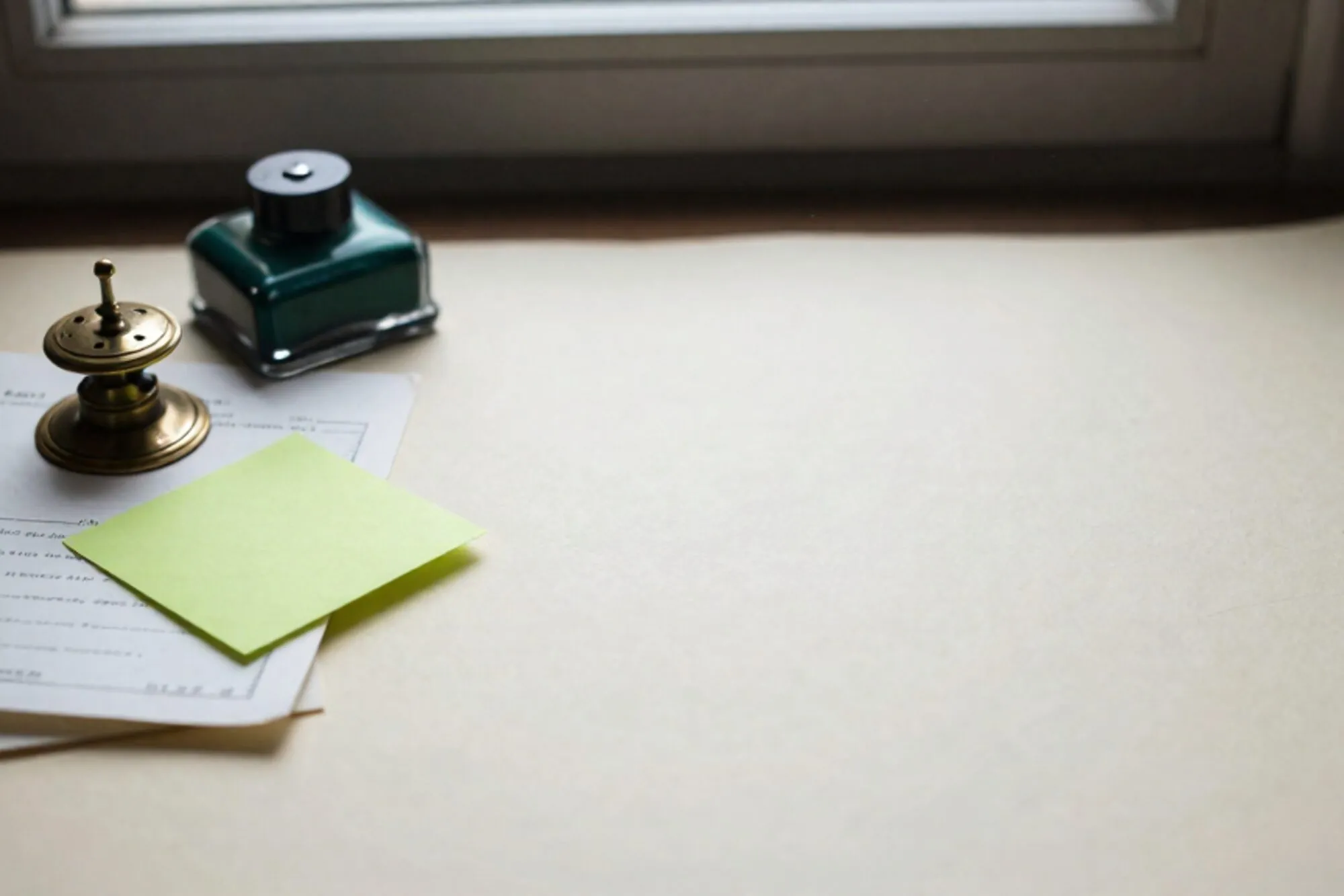 Messing relaisschakelaar naast gevouwen papieren telegram en limegroen memo op ivoren bureau met leren onderlegger.