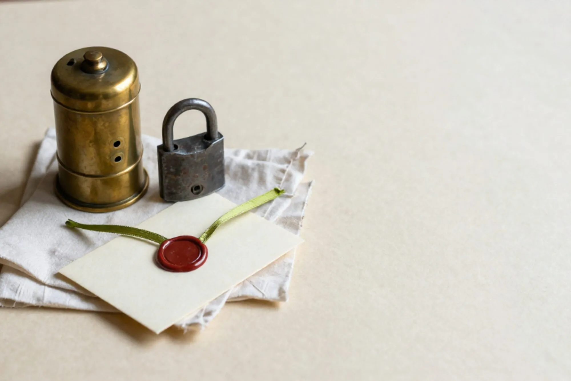 Brass fire-alarm pull, iron padlock on waxed muslin, cream index card with green ribbon, red wax seal on envelope.