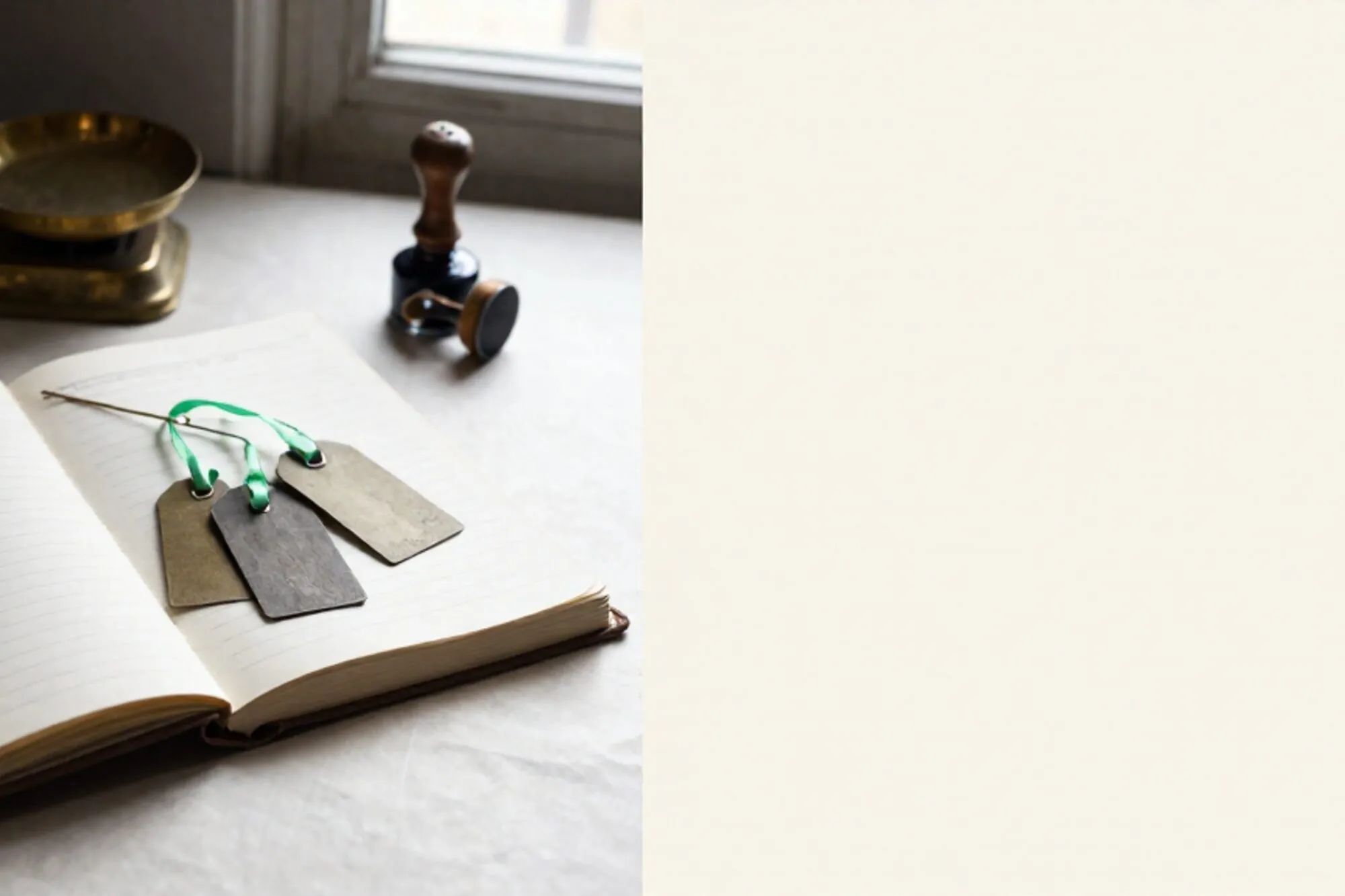 Open linen ledger, three iron tags fanned across pages, one chartreuse ribbon, brass scale, rubber stamp on ivory desk.