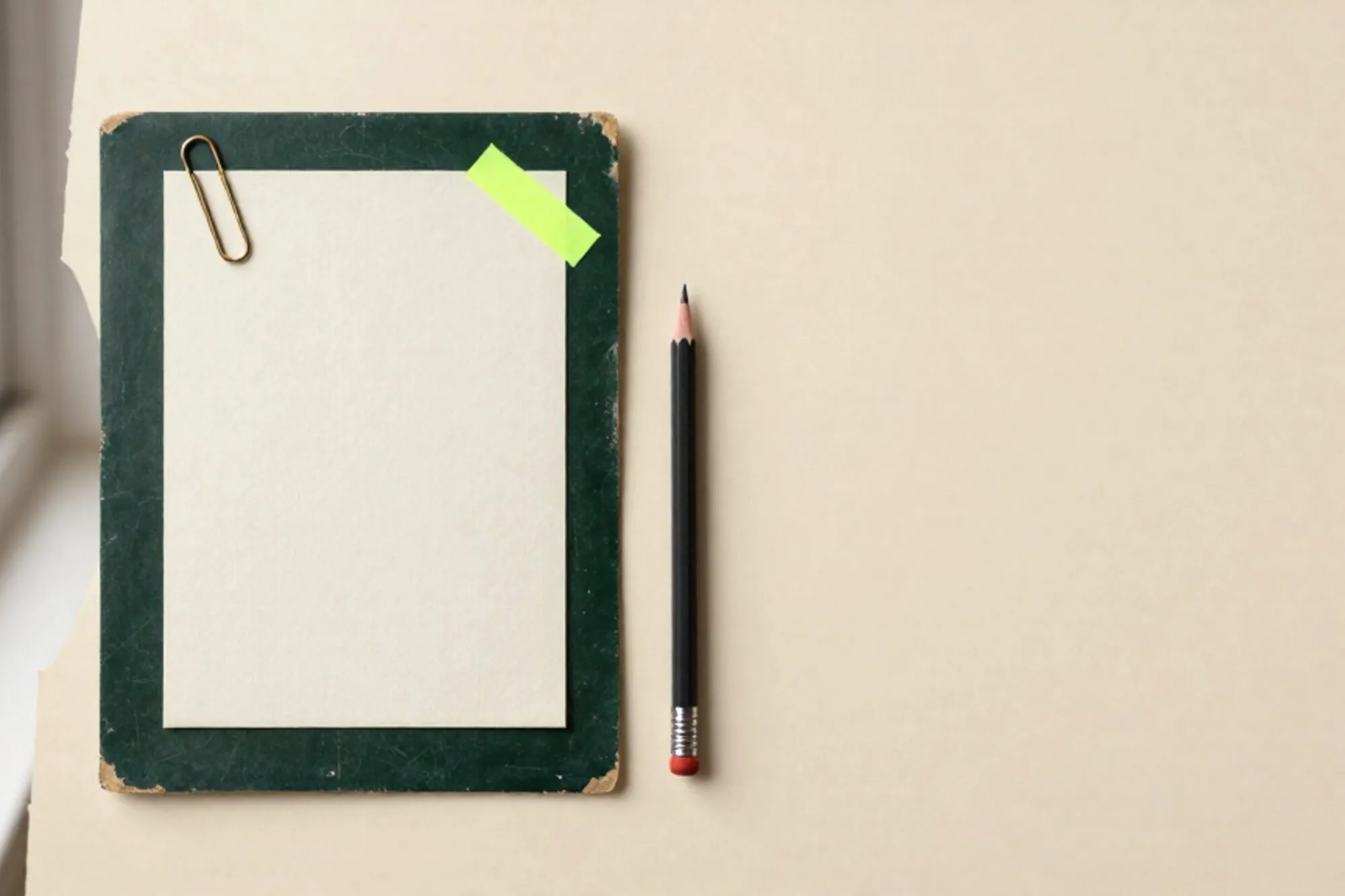 Linen brief card with brass paperclip, green sticky note, pencil and red wax seal on dark blotter.