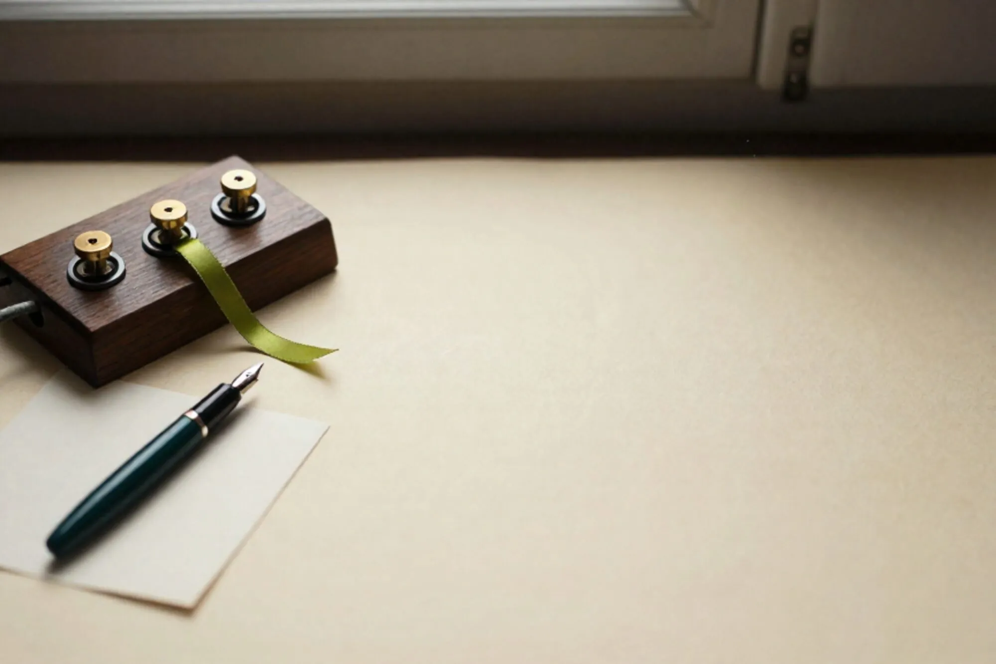 Oud houten telefoonschakelbord met messing jacks, gevlochten kabels, groen lint, indexkaart en inktpen op ivoor papier.