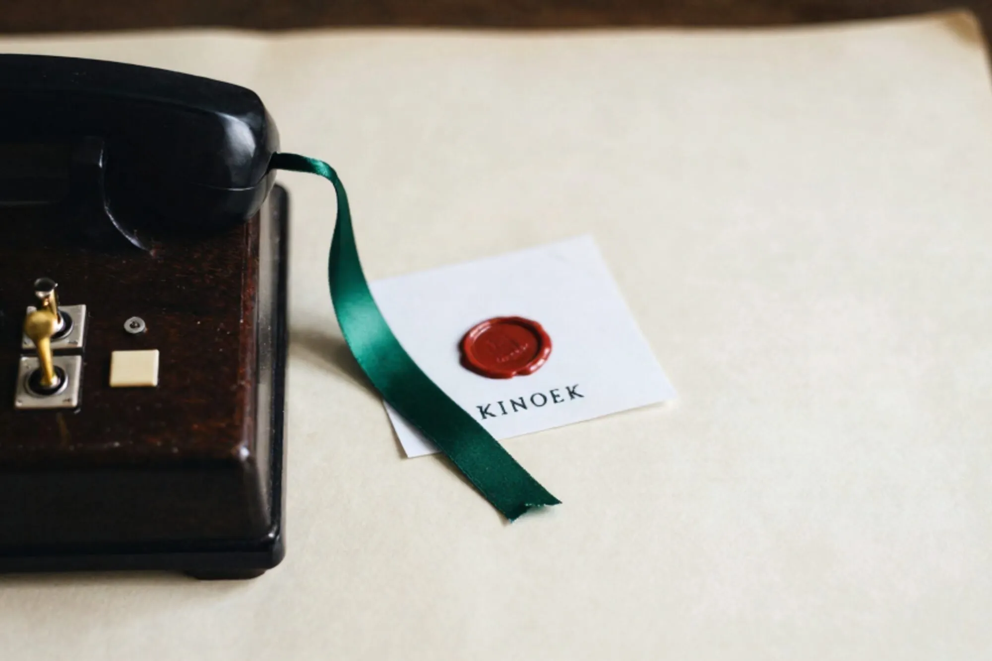 Wooden switchboard with three brass plugs in ivory jacks, frayed cord tied with green ribbon, paper slip with red wax seal.
