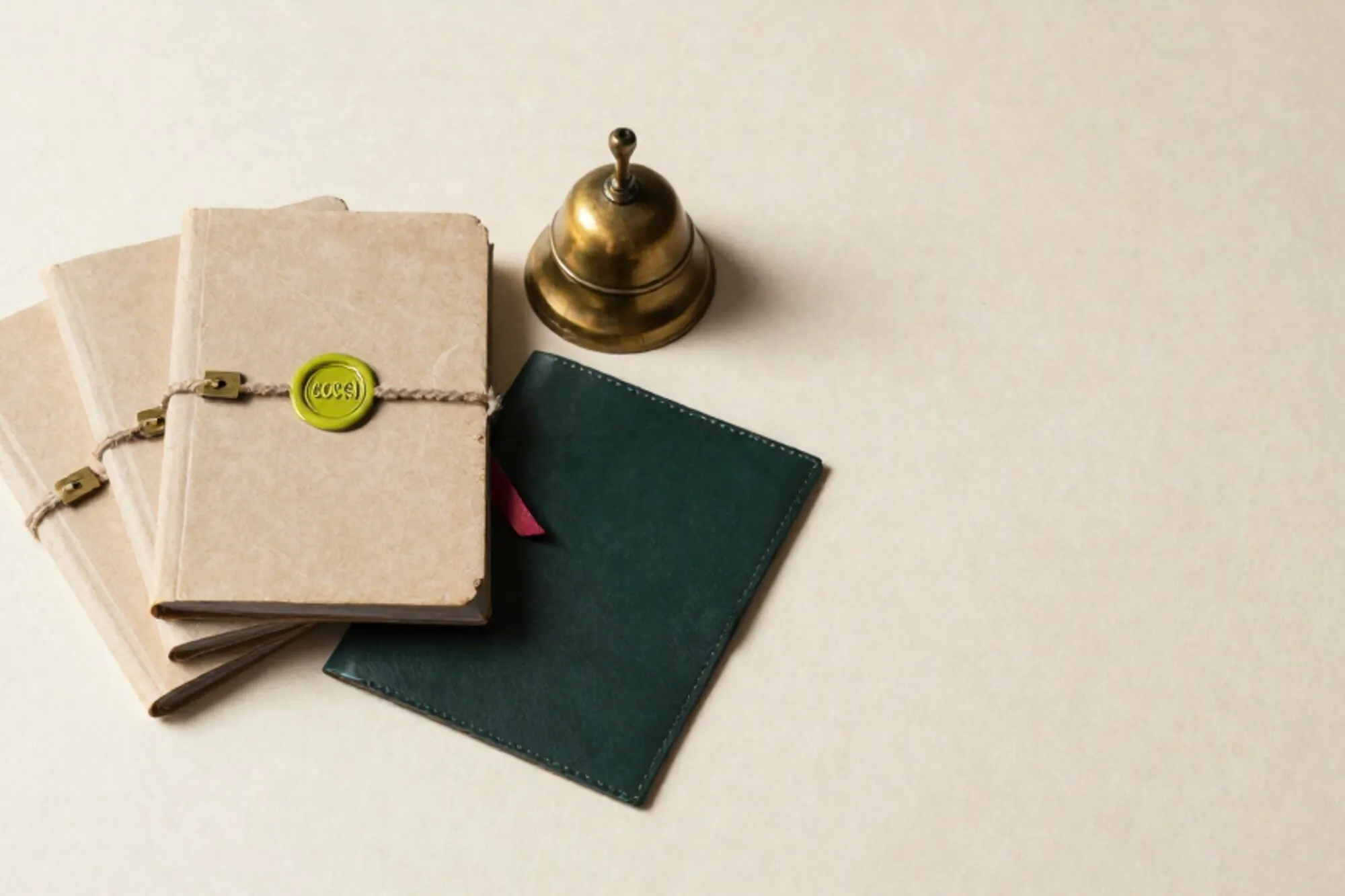 Three tied manila folders with brass tags, one chartreuse wax seal, brass bell, red ribbon, on ivory paper.