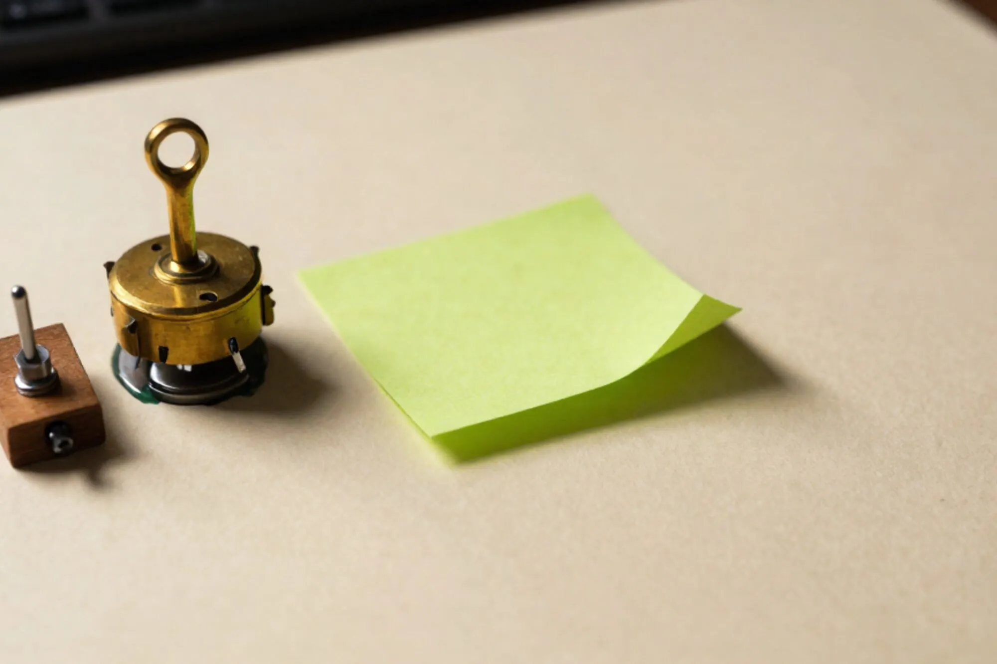 Messing relaisschakelaar naast crème papier met groene memo en houten plug op ivoorpapier, zijlicht.