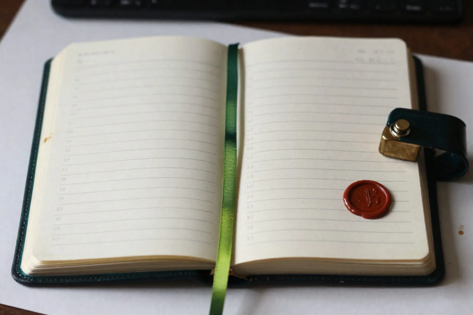 Open ivory leather ledger on pale desk, pencil ticks, green silk ribbon, brass paperweight, red wax seal, coffee ring.