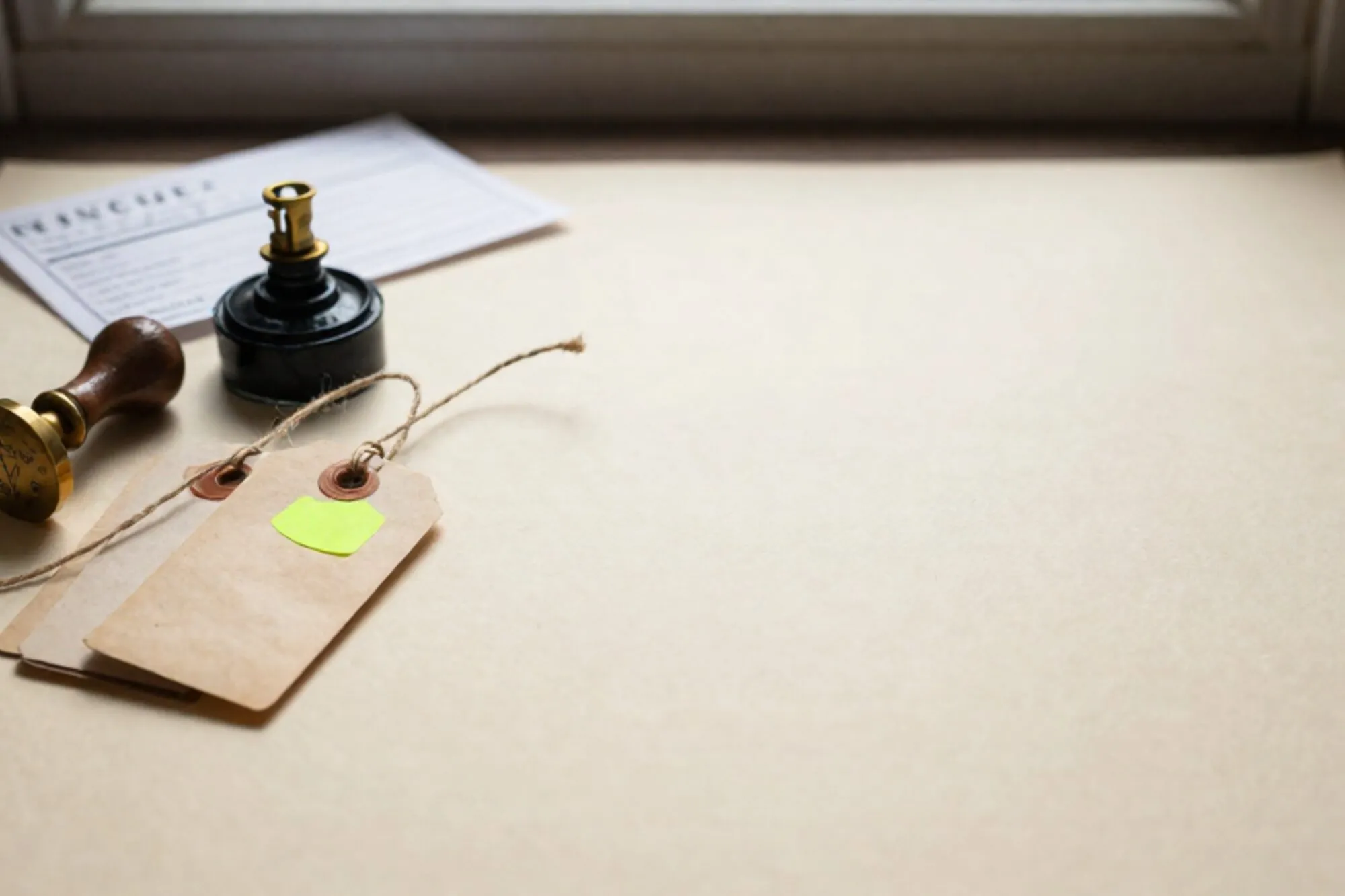 Brass customs stamp, ink pad, three twine-tied shipping tags with one green sticker, relay switch on ivory paper.