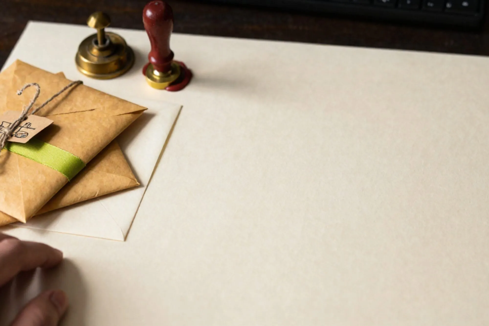 Three kraft envelopes tied with twine on an ivory desk, one with a green ribbon, brass relay, paper docket, wax seal.