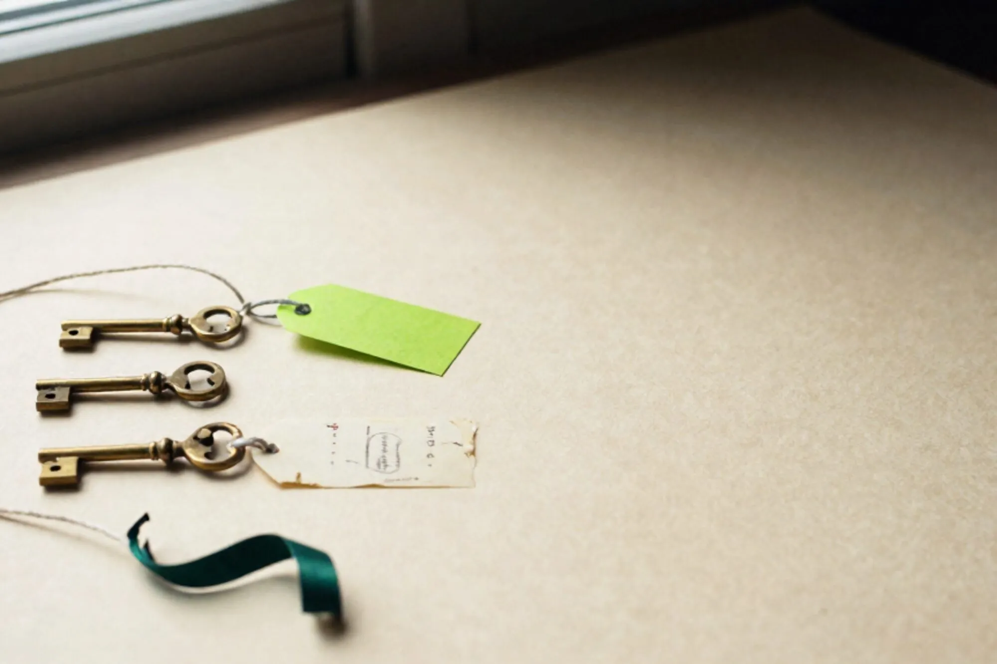 Three brass telegraph keys on ivory paper, linen threads, green tag on middle key, cream index card, ink ribbon.