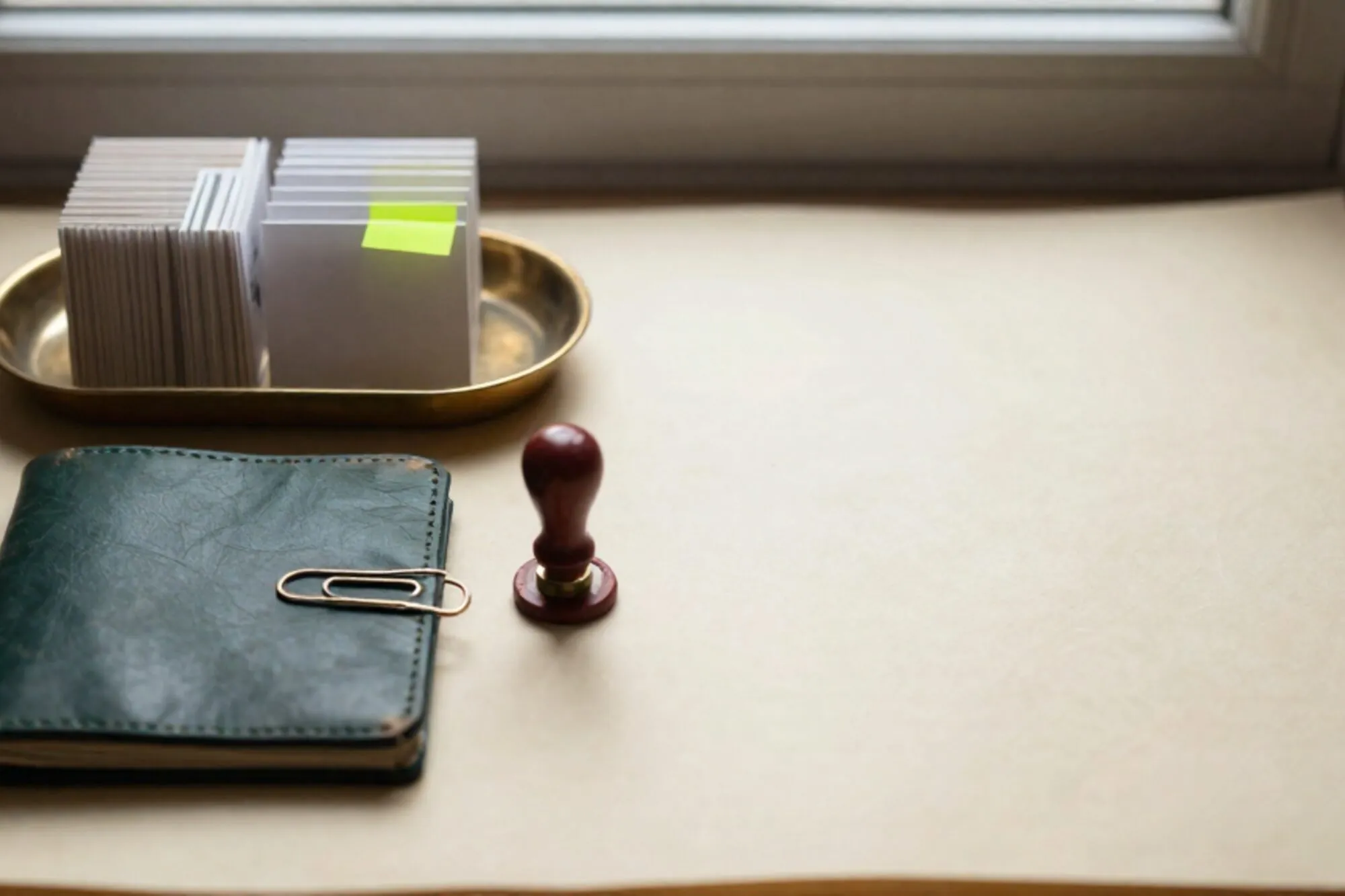 Messing kaartenbak met papieren tickets op ivoren bureau, één ticket met groen tabje, leren onderlegger, lakzegel.
