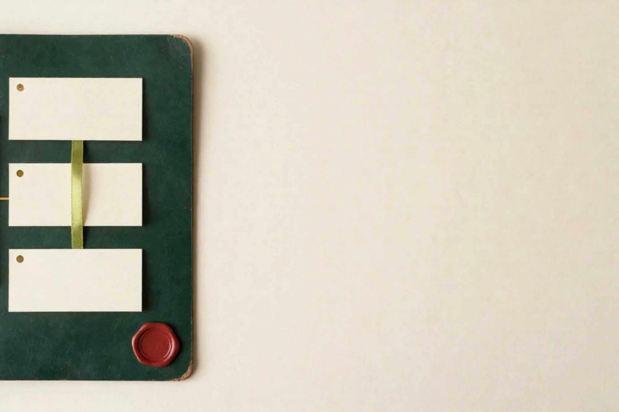 Forest-green leather blotter with three cream index cards, brass divider, green ribbon, red wax seal on ivory paper.