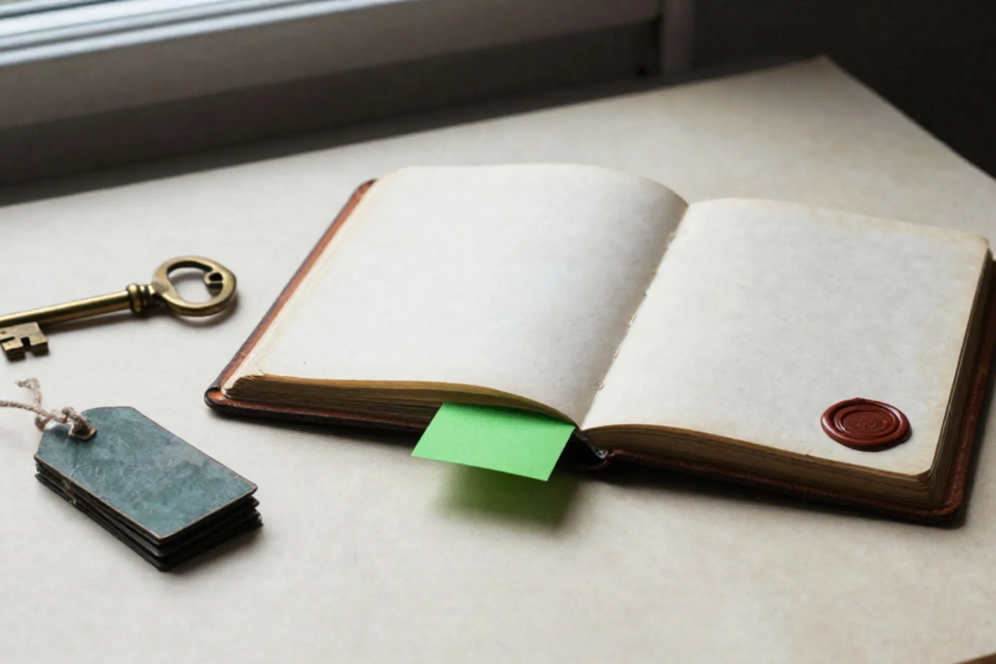 Open leather logbook with brass key on spine, iron tags with twine, green index card, red wax seal on ivory paper.