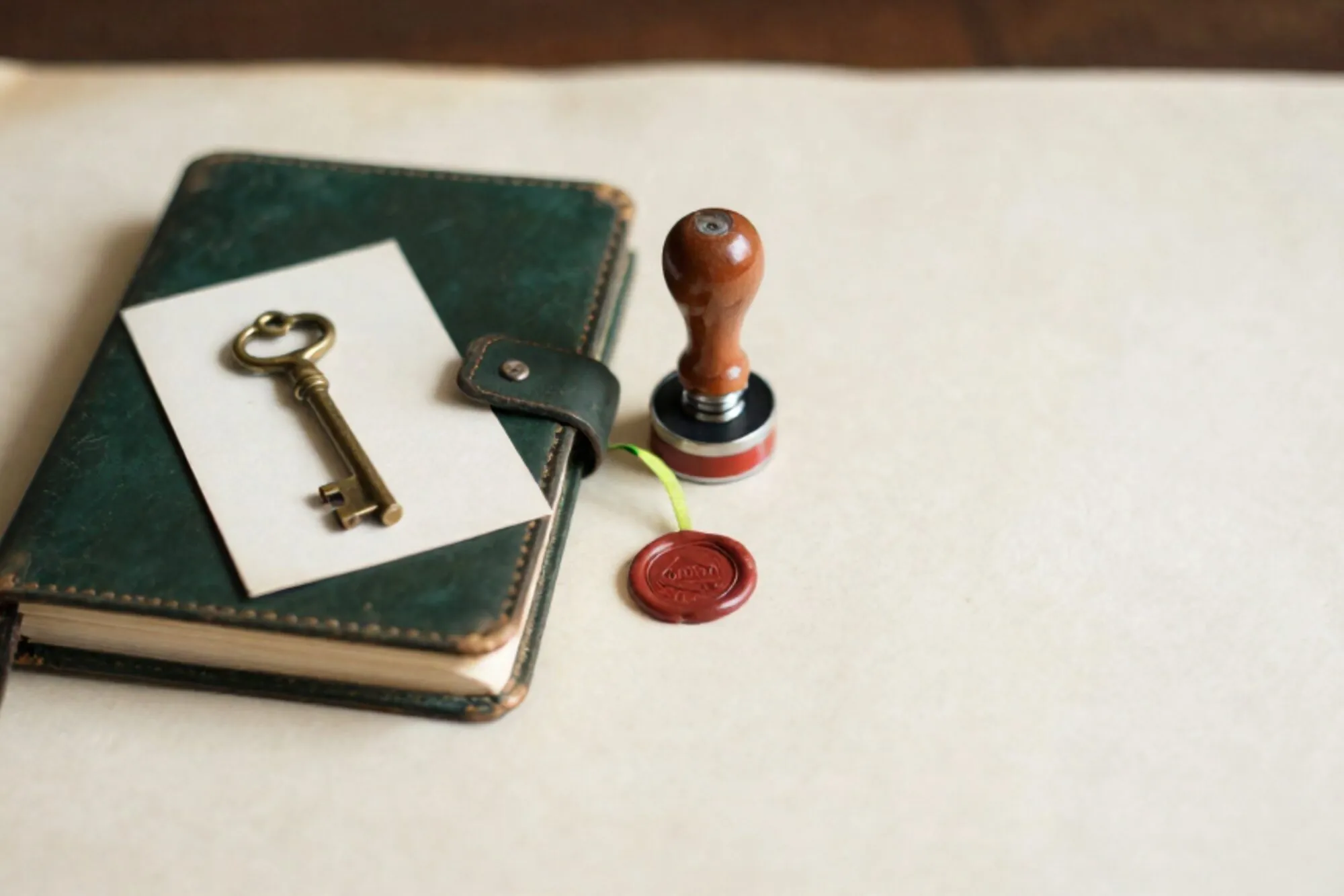 Open groen leren logboek, koperen sleutel op crème kaart, rubberstempel met groen lint, rood waxfragment op ivoor papier.