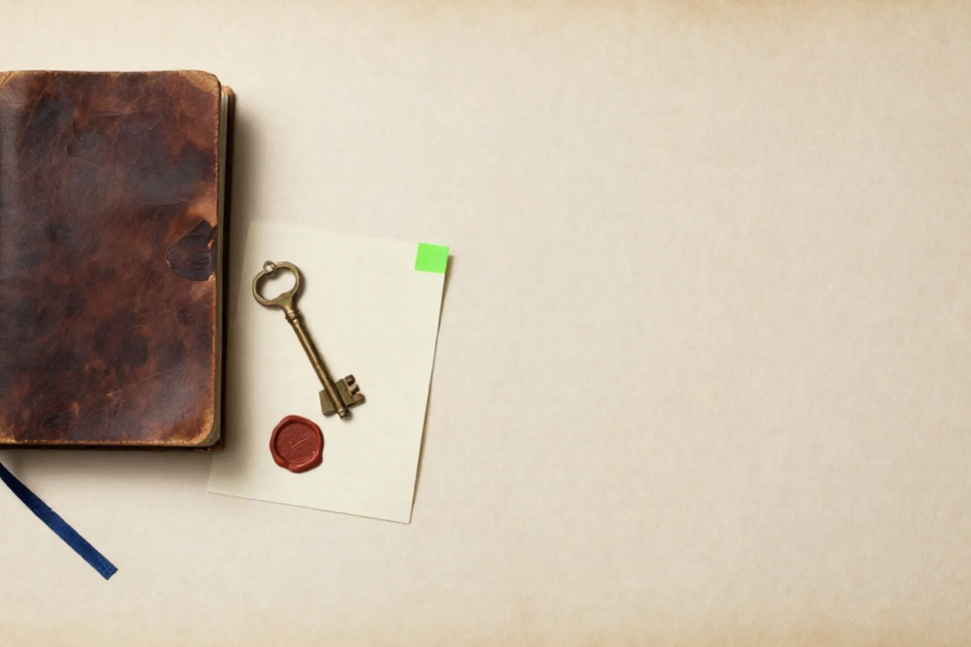 Leather logbook with blue ribbon, brass key on index card, wax stamp, green tab, red wax seal on ivory paper.