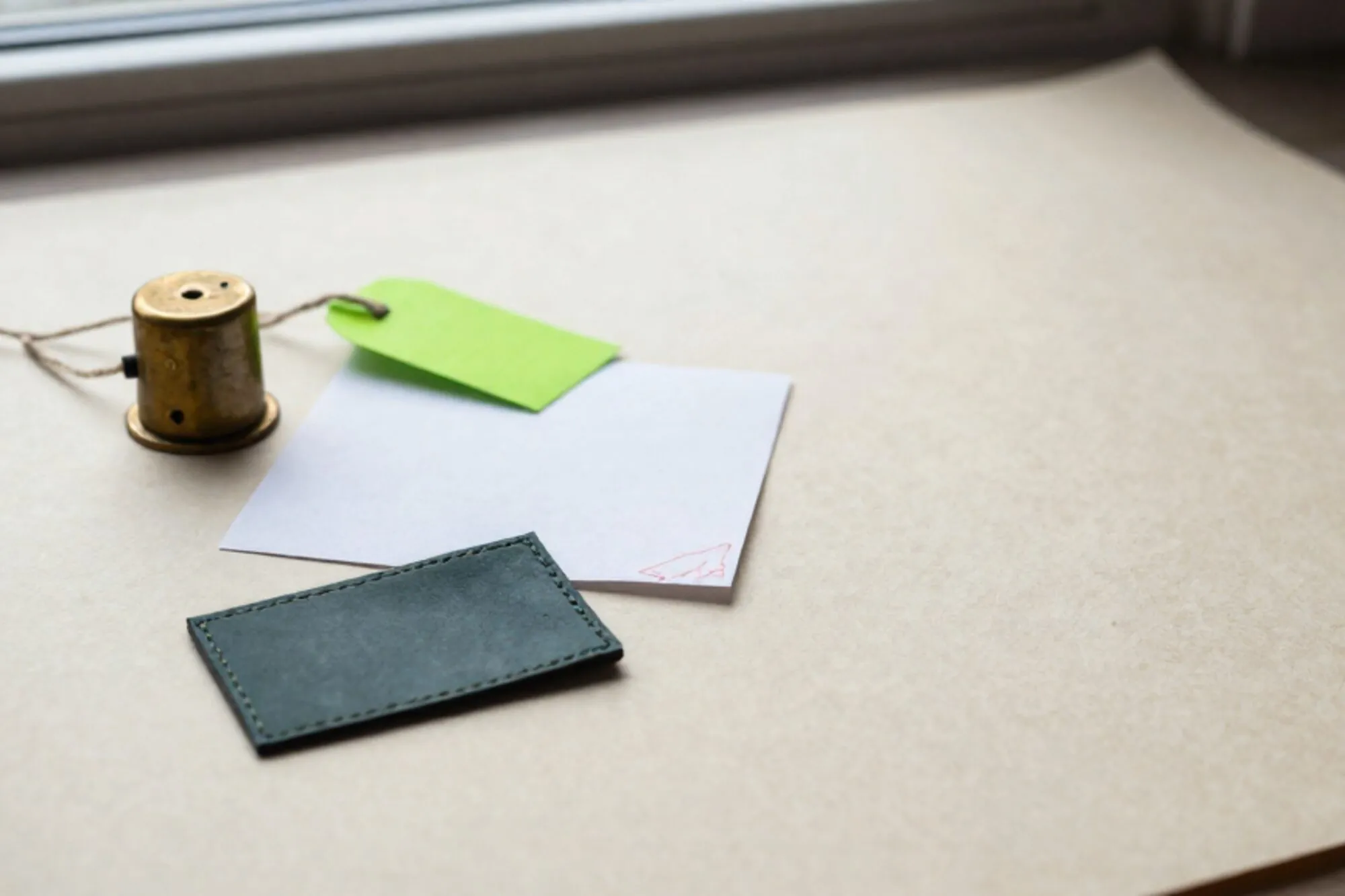 Brass relay on ivory blotter, green paper tag on linen thread, carbon-copy slip with red stamp, leather pad edge.