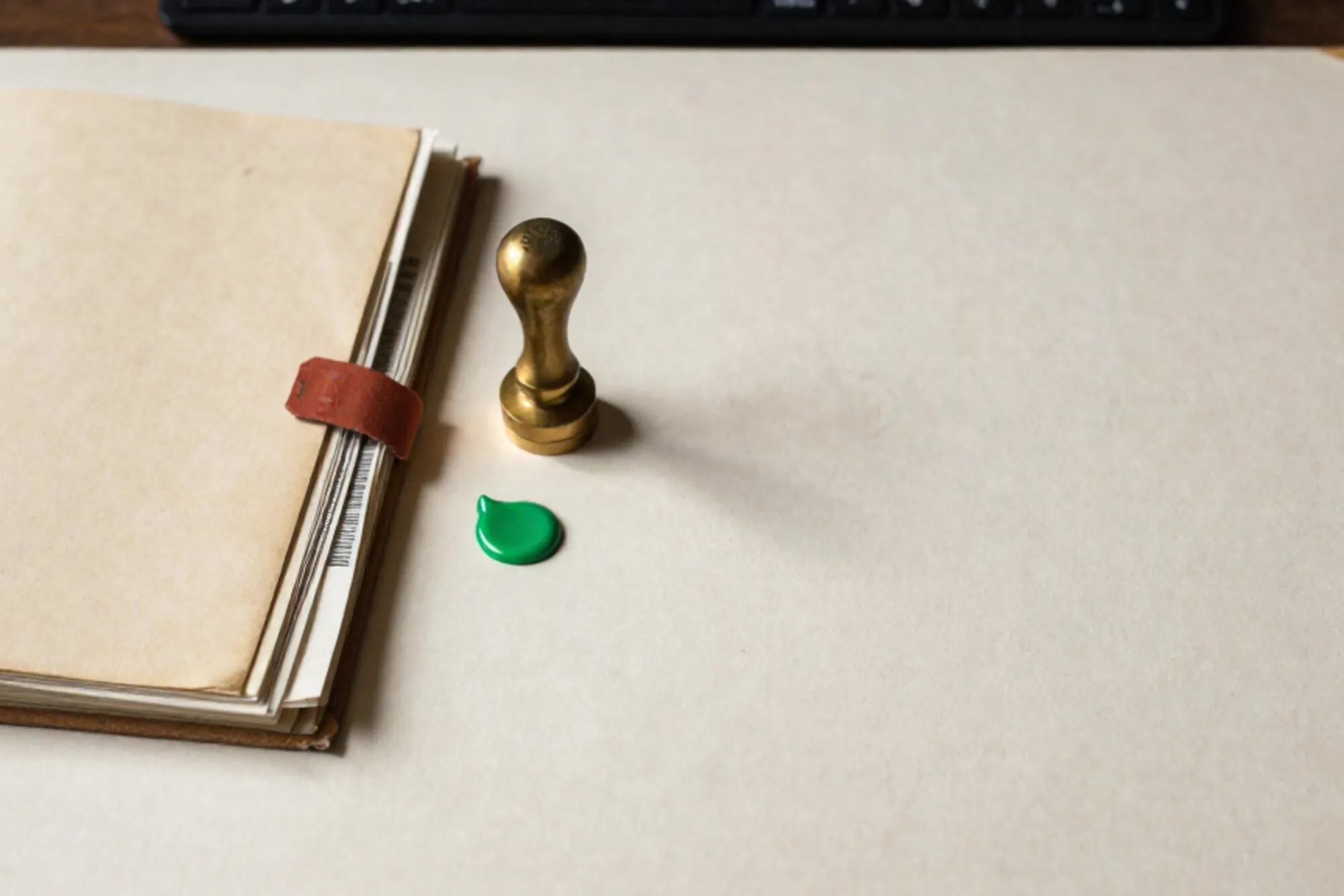Manila dossier ajar with carbon copies, brass wax seal, green wax drop, red ribbon tag on ivory desk.