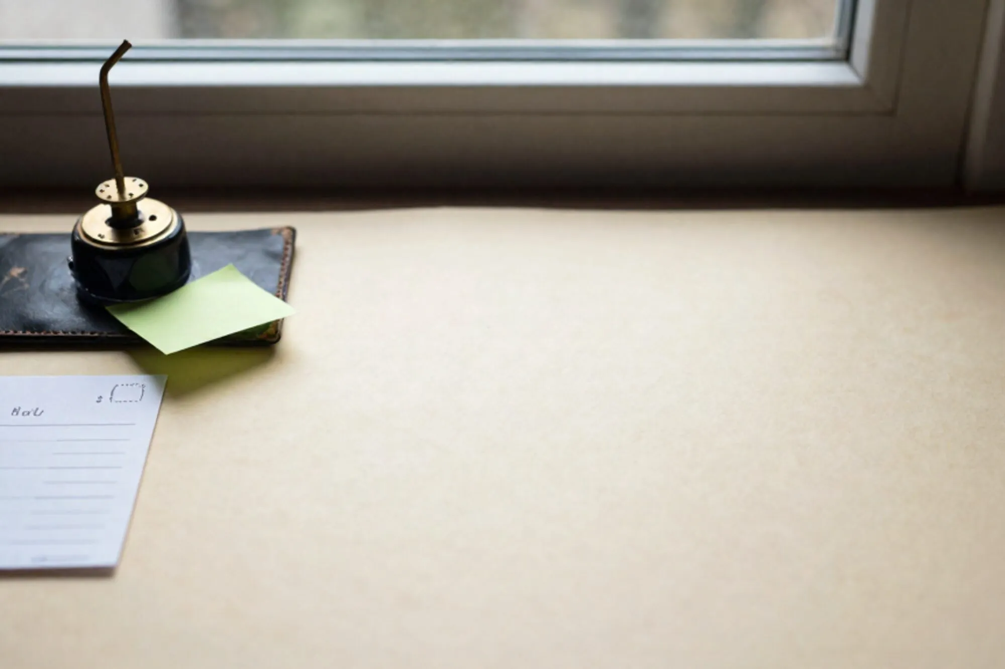 Messing relais en gevouwen telegram op ivoren bureau, groene memo, donkergroen leren onderlegger, licht van zijraam.