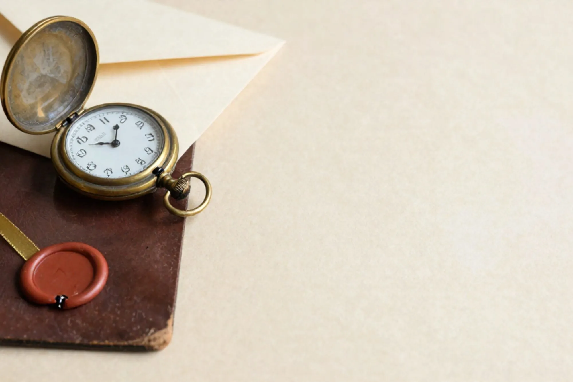 Messing zakhorloge op leren onderlegger, crème envelop met limoenlint, gebroken rood lakzegel, ivoorpapier.