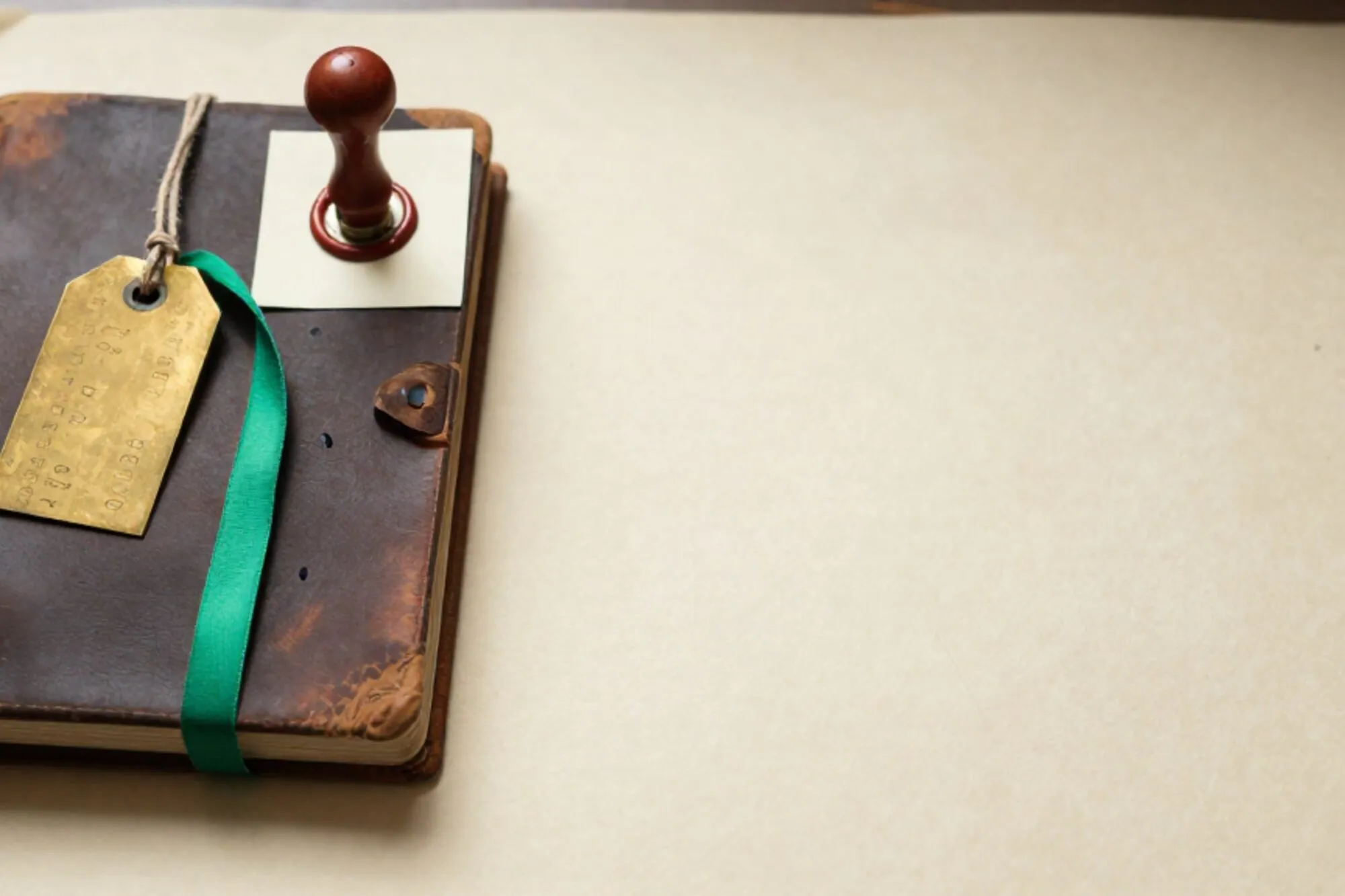 Open leather shipping logbook on ivory paper with brass freight tag, linen twine, green ribbon, red wax seal.