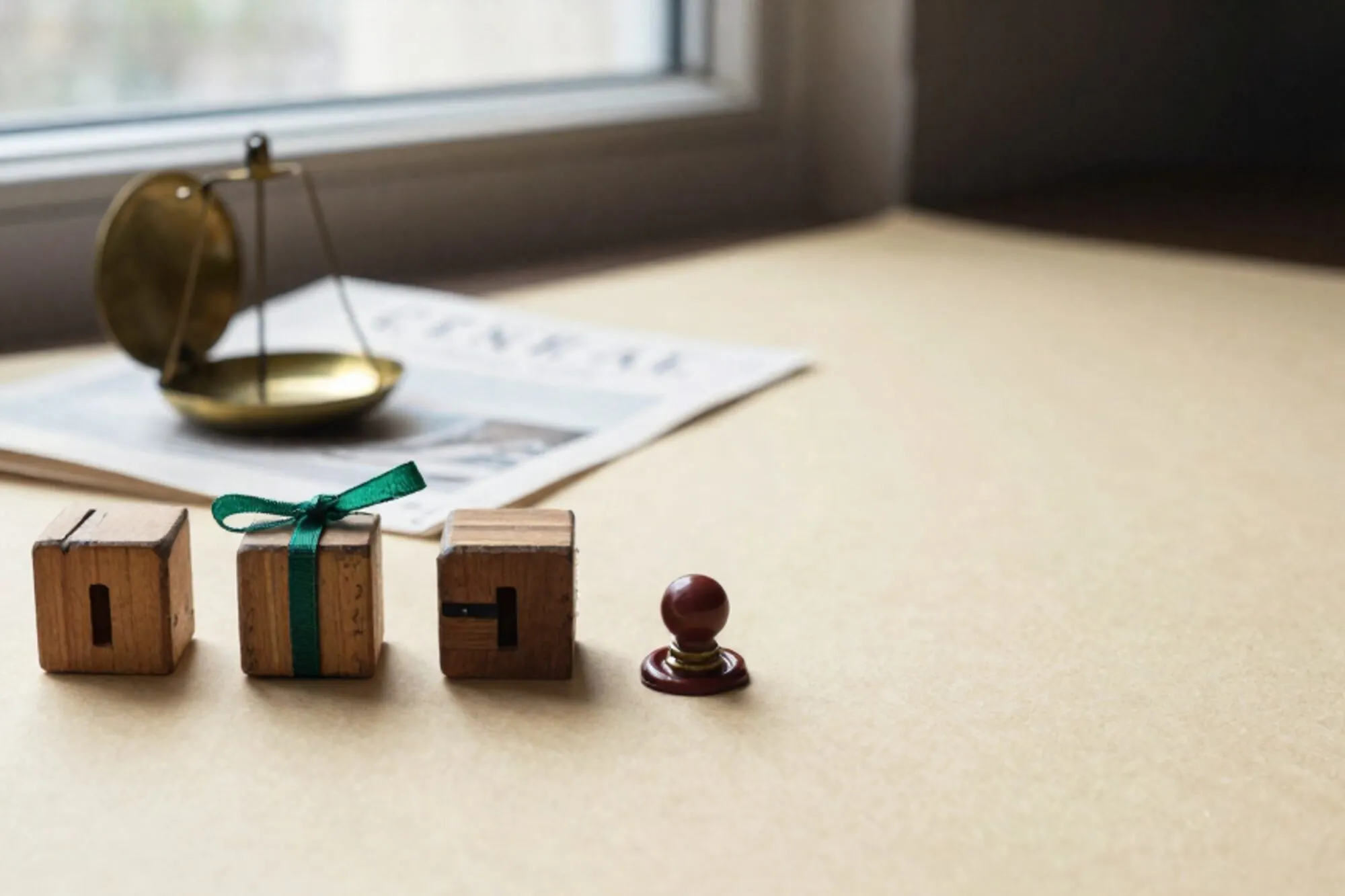 Three notched wooden tally blocks, one with green ribbon, brass scale, folded ledger paper, red wax seal on ivory.