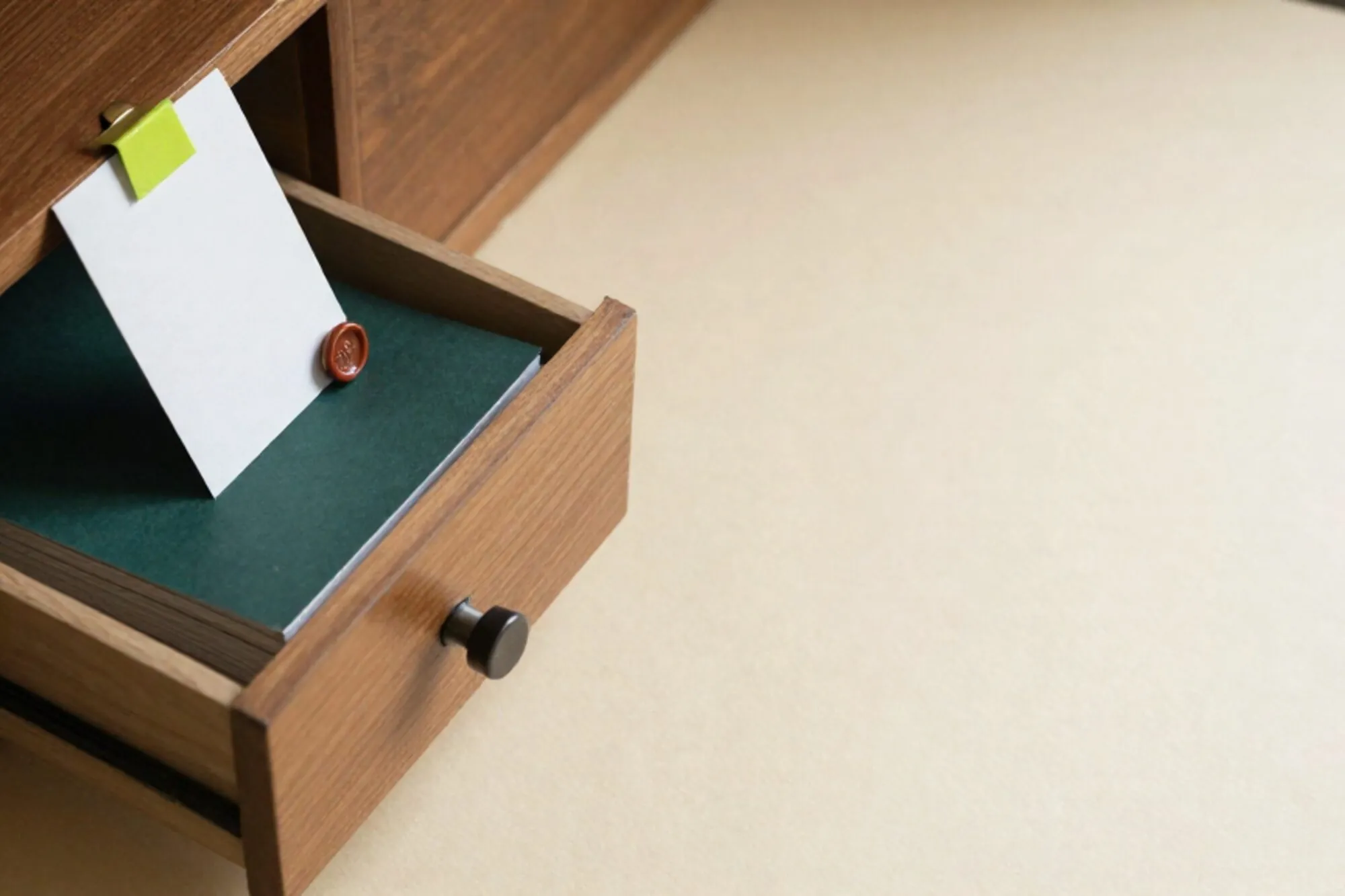 Open eiken kaartenbak met één kaart in limegroen getabd, stapel grootboekpapier met rood waszegel op ivoren ondergrond.