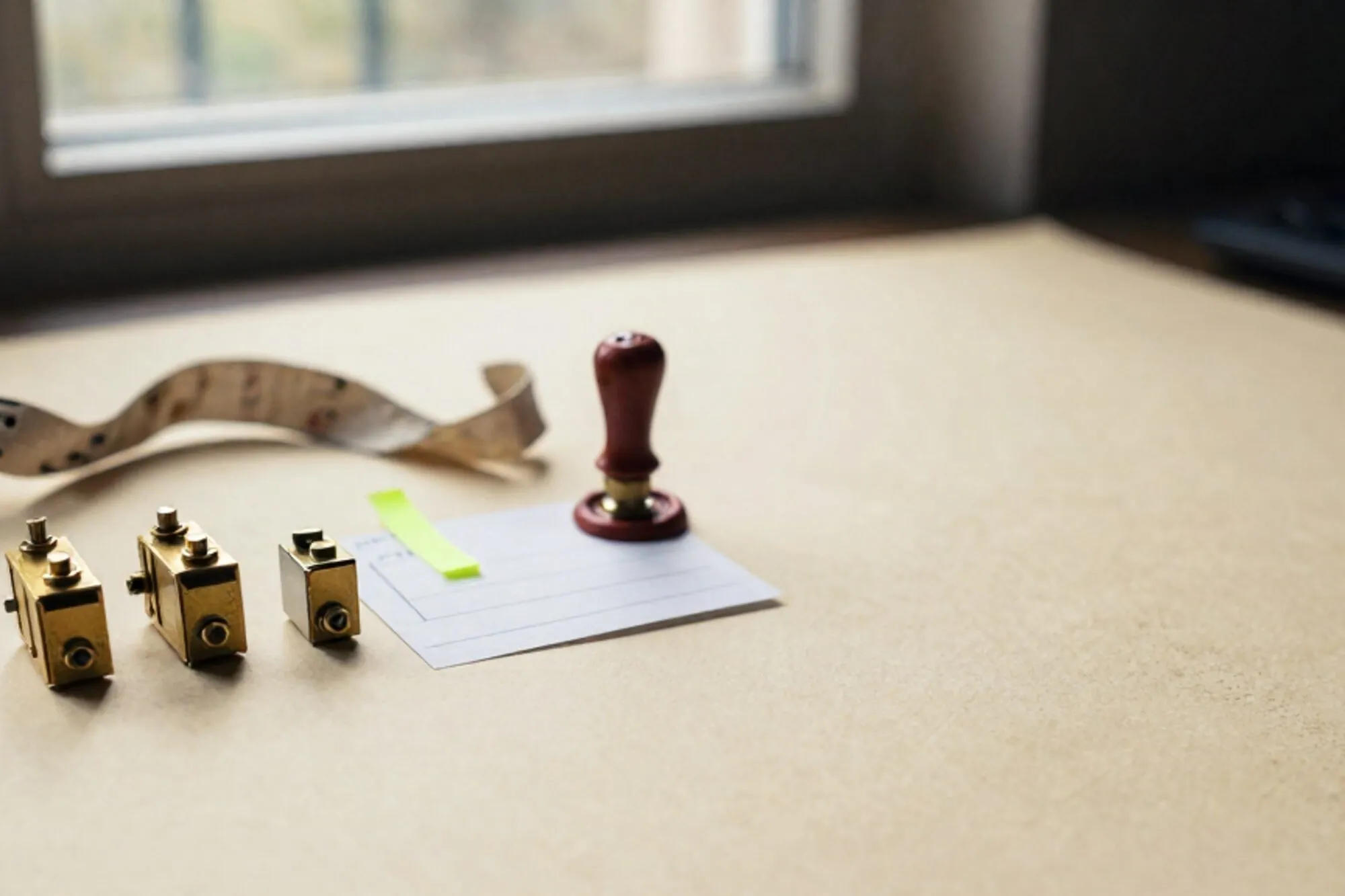 Three brass relays in a row, a paper telegram with a green tab, linen ribbon and red wax seal on ivory paper.