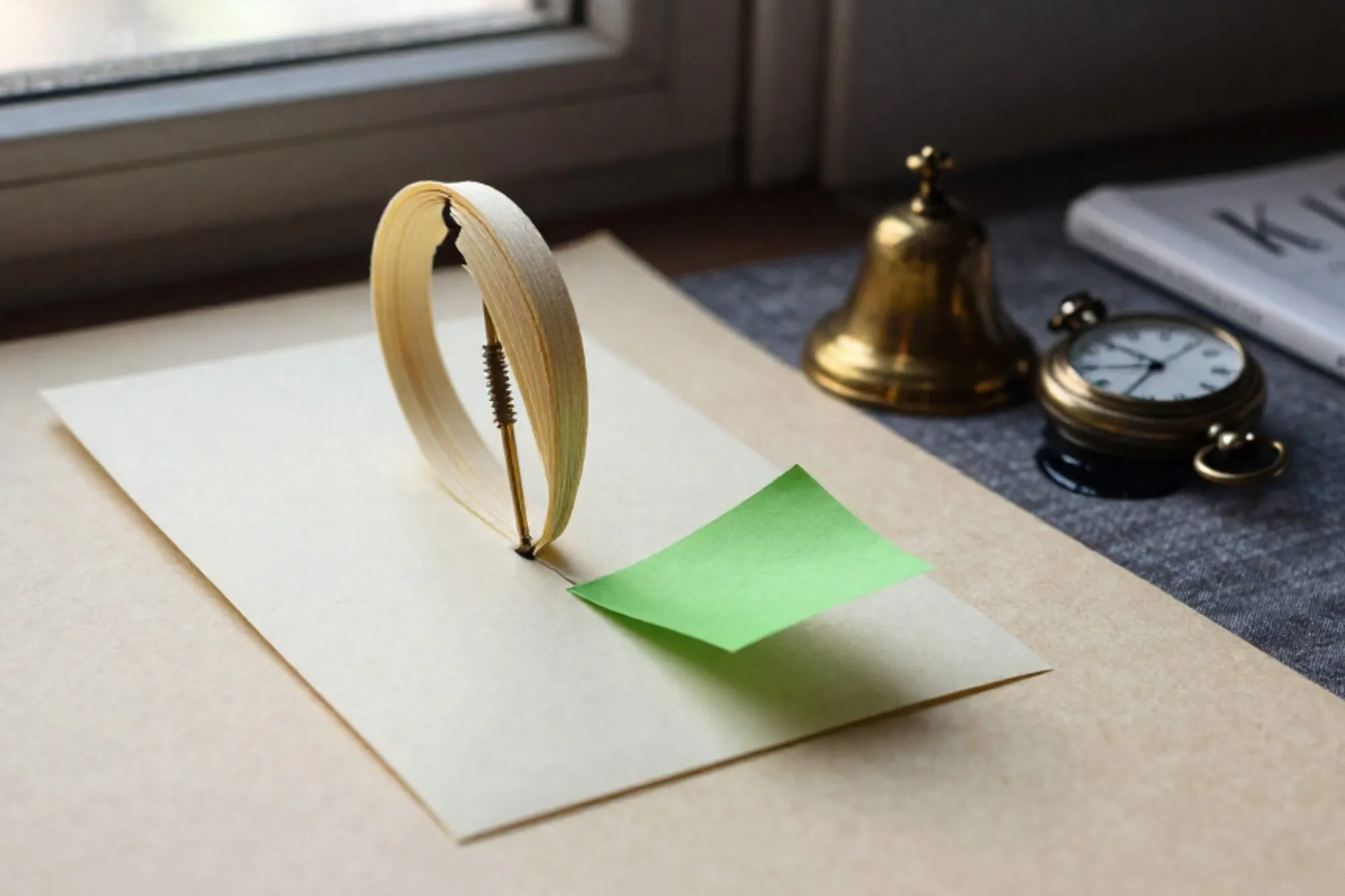 Brass spindle stacked with paper receipts on ivory blotter, one green carbon slip, tipped bell, pocket watch, ink linen.