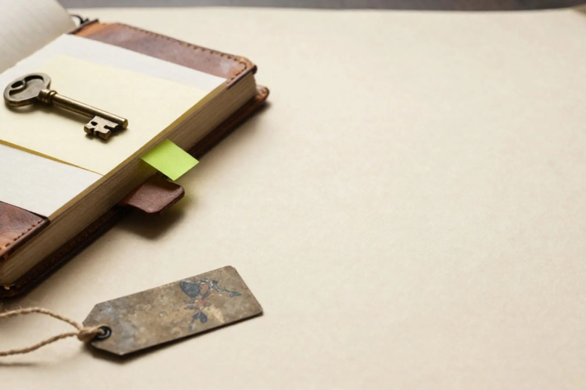 Open leren logboek met messing sleutel op crème kaart, groen tabje, ijzeren label aan linnen touw op ivoor papier.