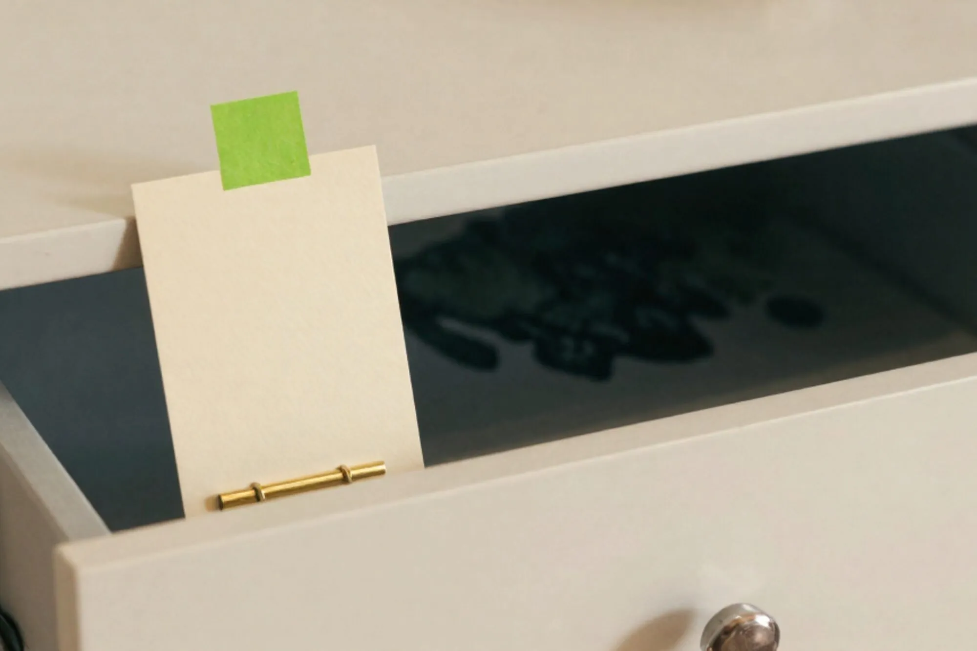 Oak index-card drawer half open on ivory paper, one cream card with a chartreuse flag, brass divider beside it.