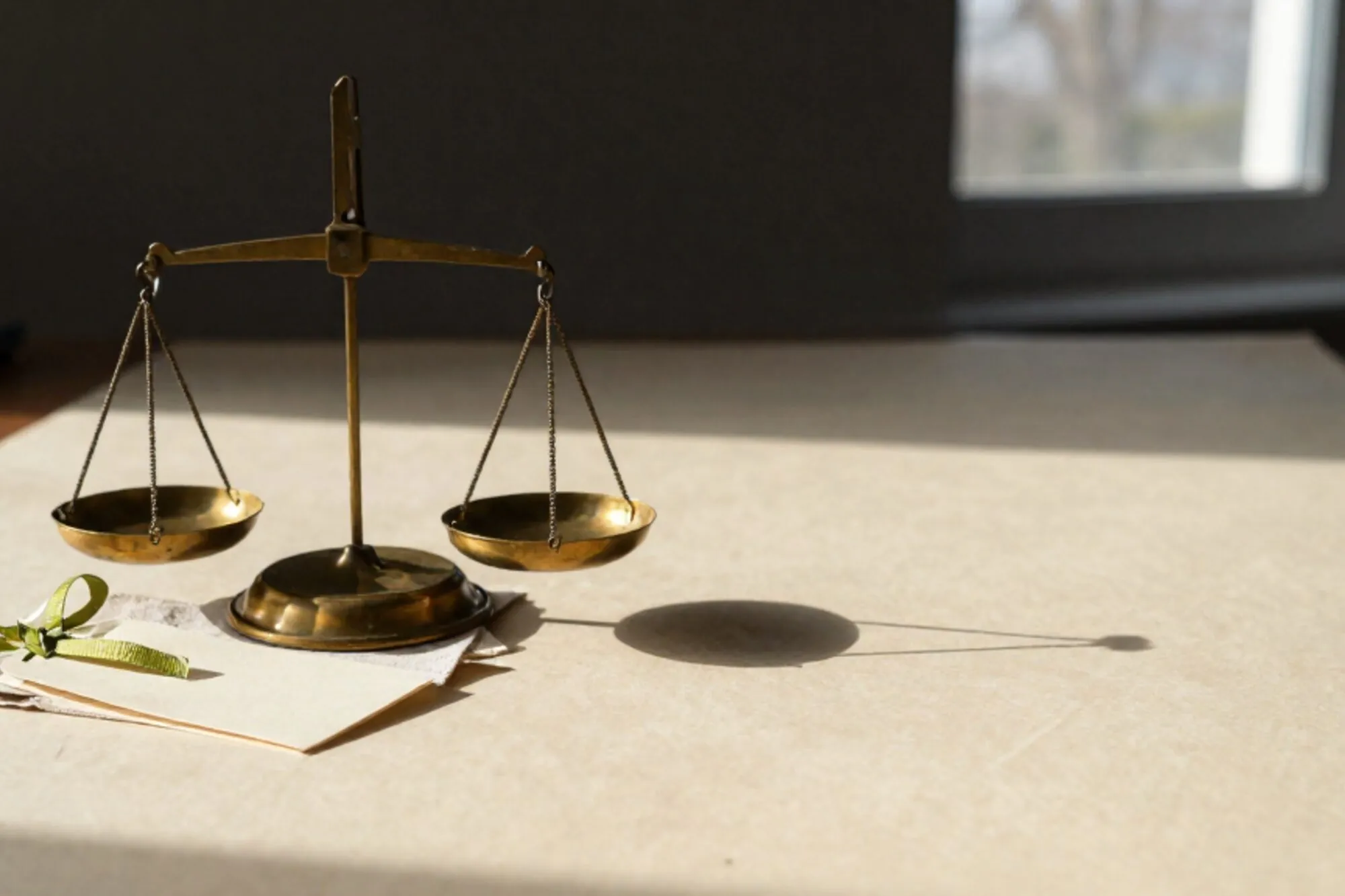 Drie messing weegschalen op ivoren bureau, groen lint om kleinste, linnen lap, zacht raamlicht.