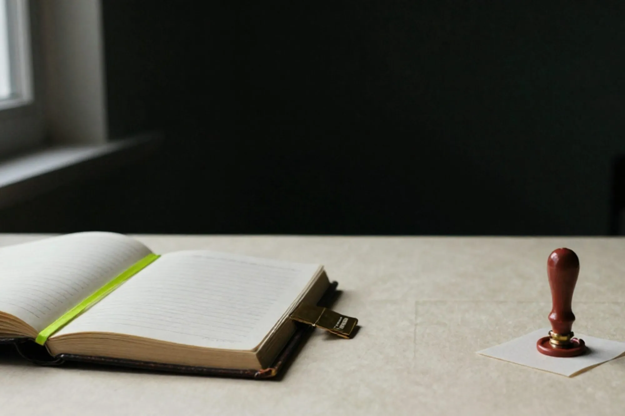 Weathered leather ledger half-open on ivory linen desktop, chartreuse ribbon marking an index card, brass divider, red wax seal.