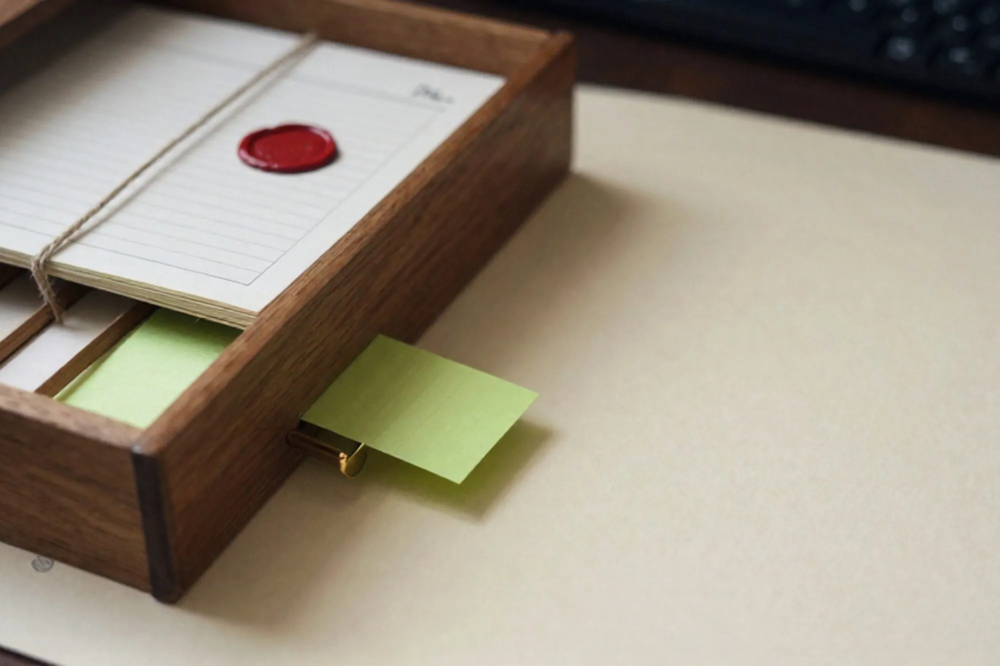 Open oak index-card drawer, linen-tied ledger stack, brass divider, green card, red wax seal on ivory paper.