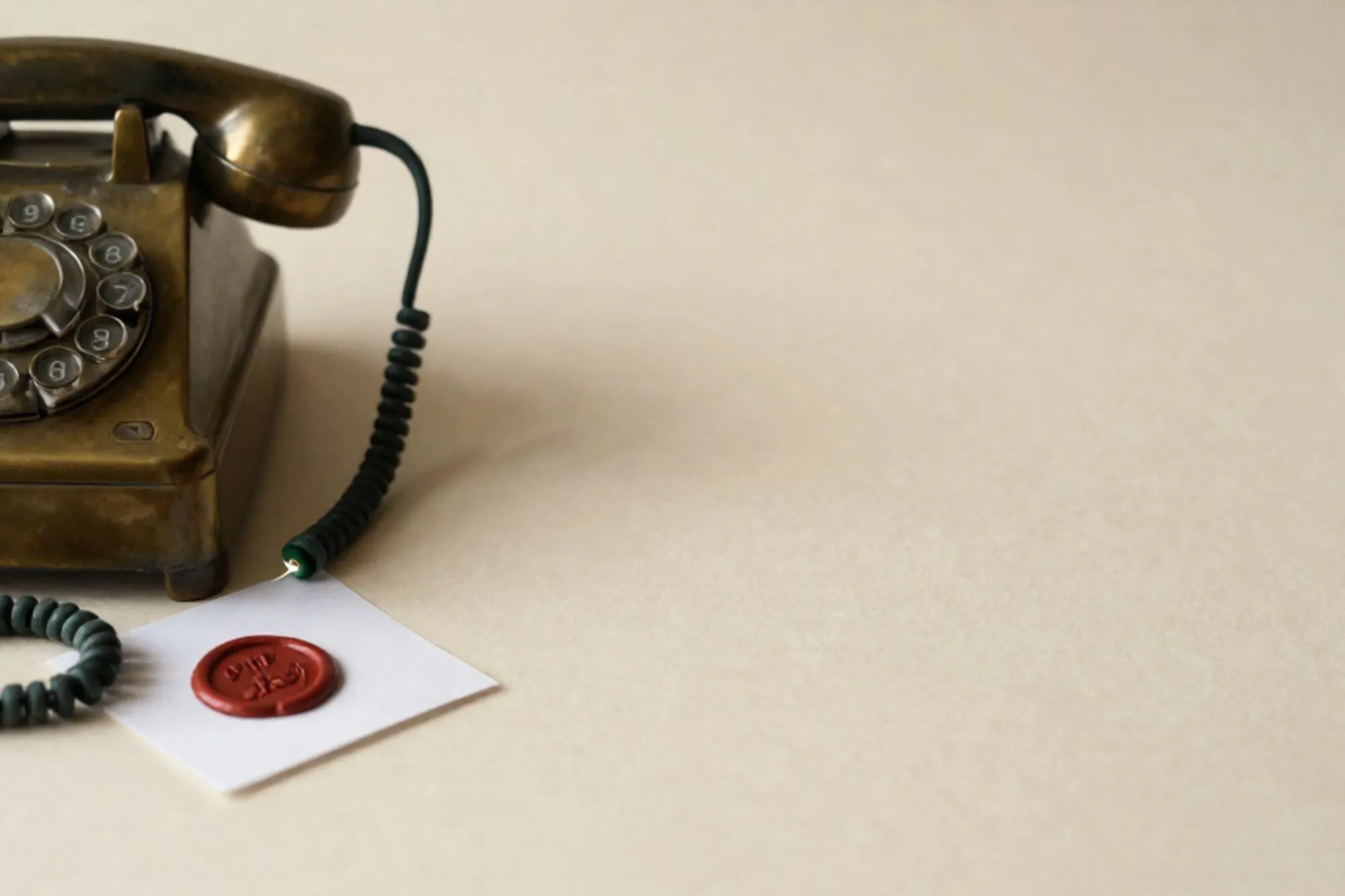 Brass telephone switchboard with looped cords, one glowing green plug, red wax seal on folded card, ivory paper.