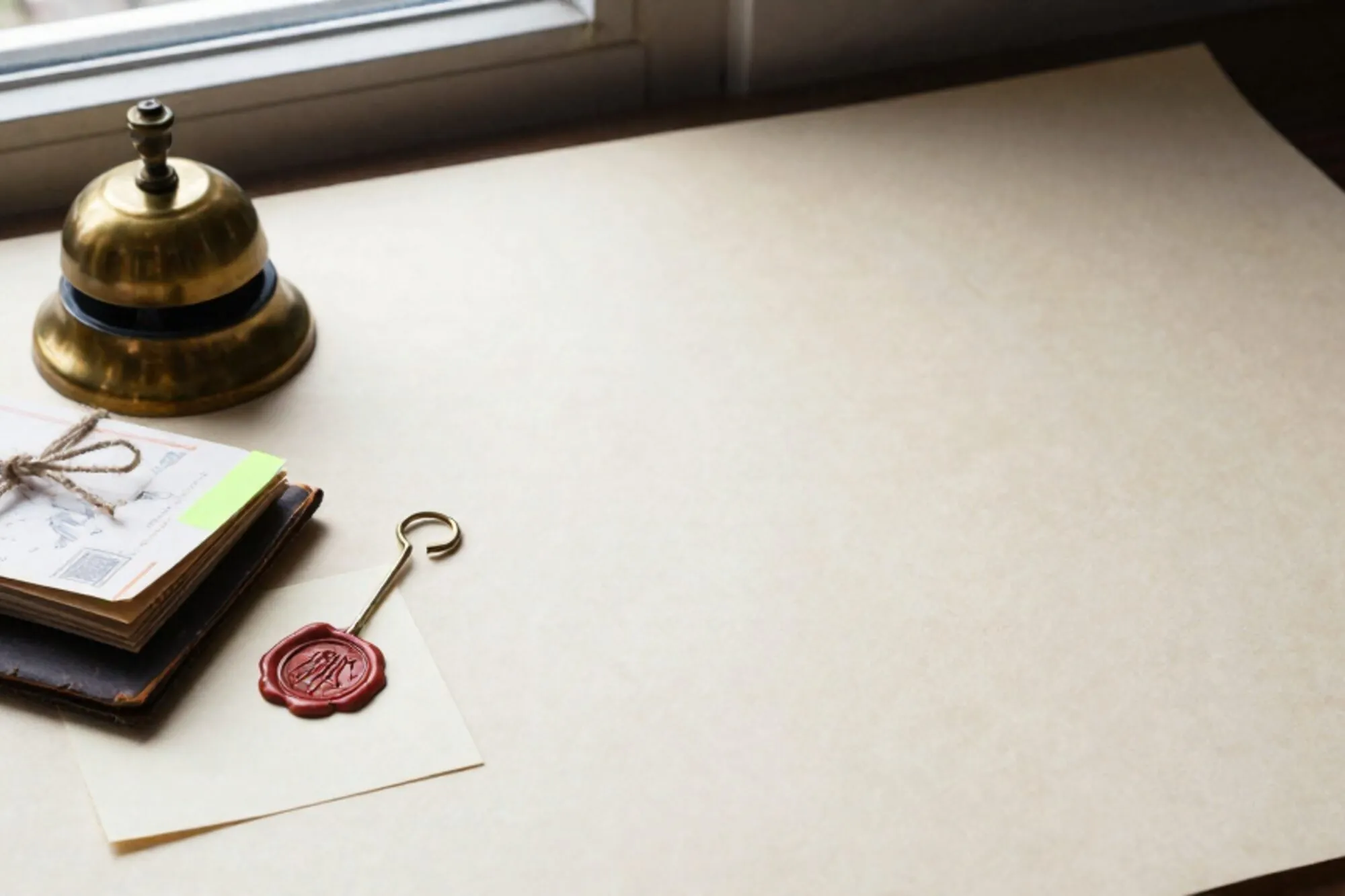 Messing bureaubel, gevouwen telegrambriefjes met linnen touw en groen labeltje, leren onderlegger, lakzegel op ivoorpapier.