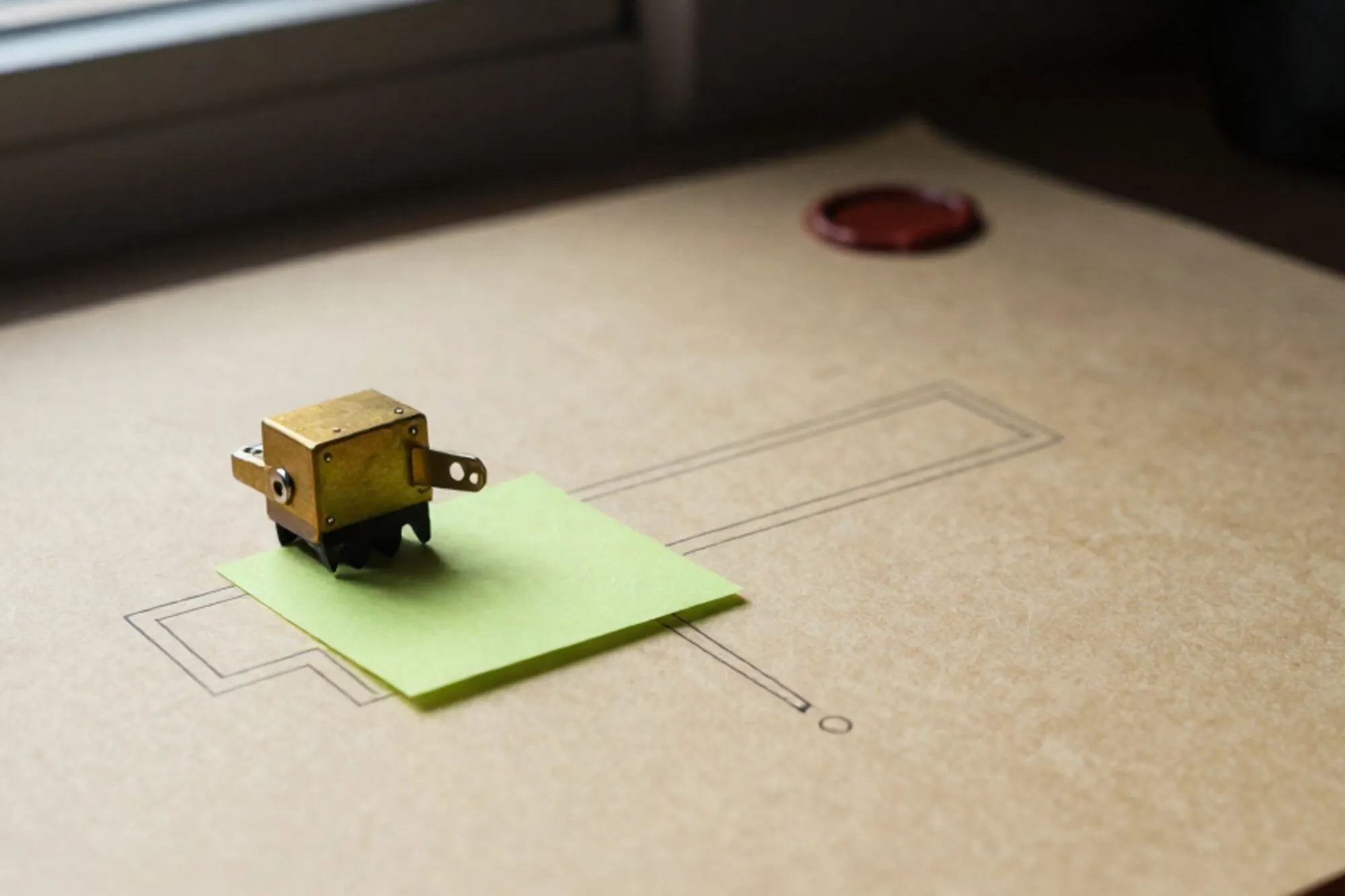 Brass relay on ivory paper diagram, green sticky note beneath, broken red wax seal, side window light.