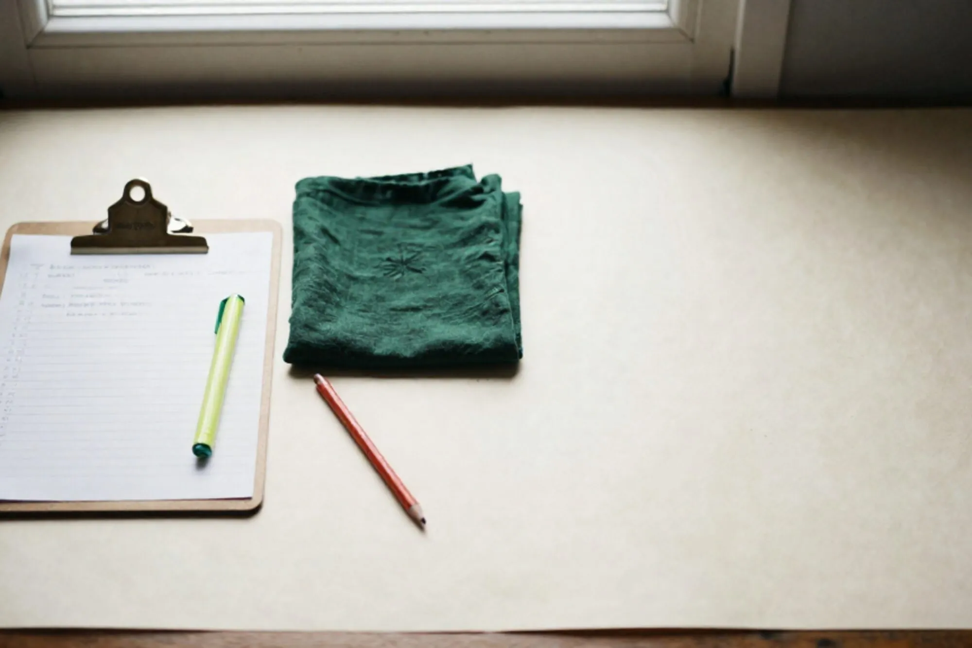 Veterinary clipboard with handwritten note, folded linen cloth, green ribbon, wax pencil on ivory paper surface.