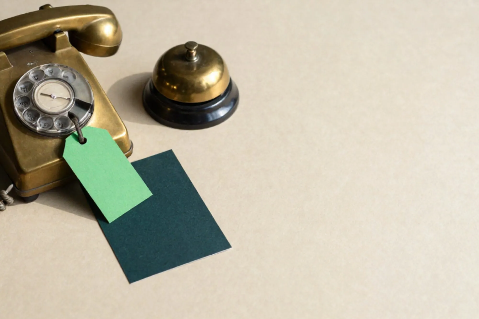 Koperen schakelbord met drie gevlochten snoeren, groen label aan middelste snoer, inktkaart en belletje op ivoren bureau.