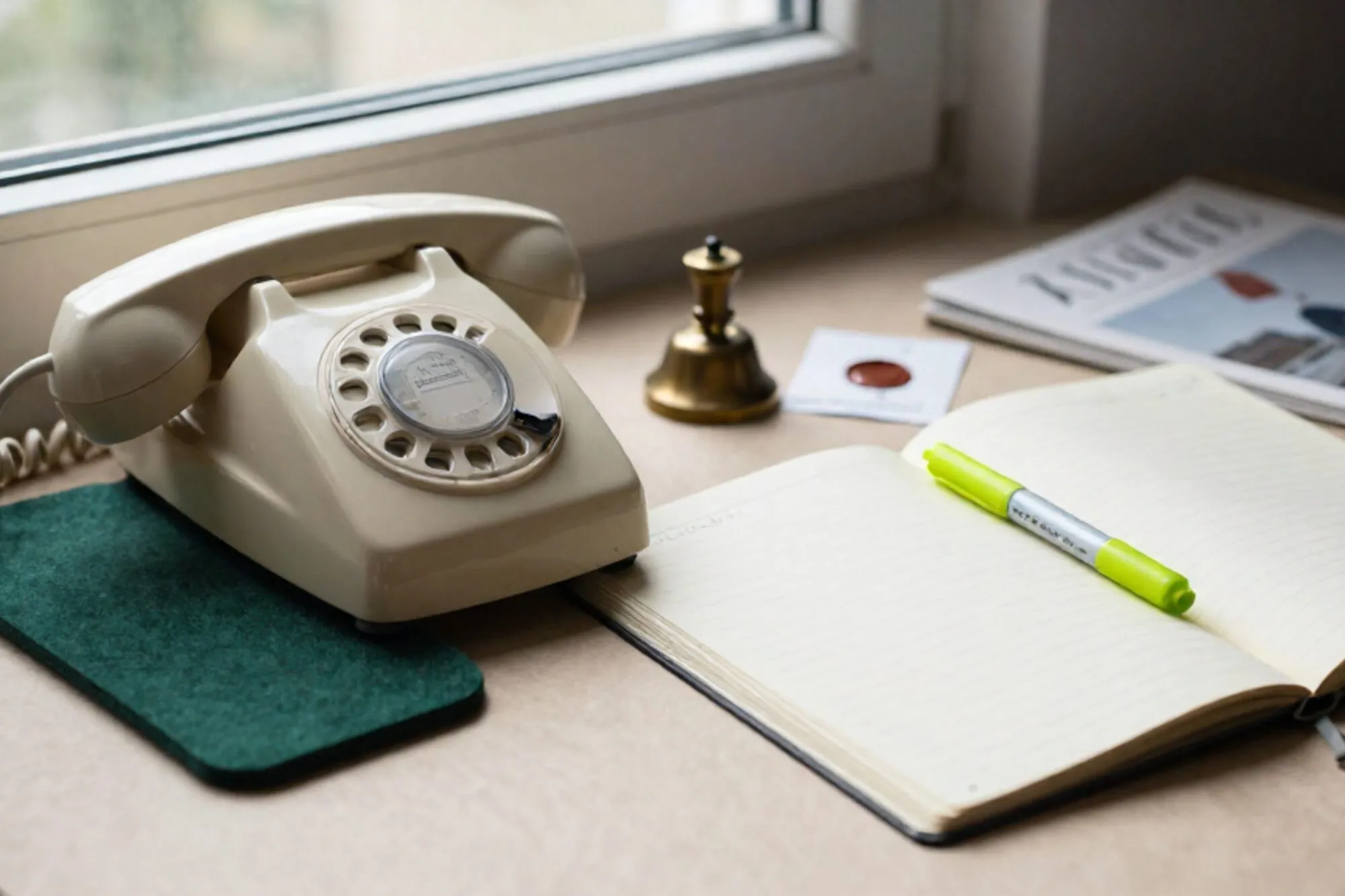 Crèmekleurige Bakelieten telefoonhoorn op groen vilt, ivoren agenda met groen lint, koperen bel, rood lakzegel.