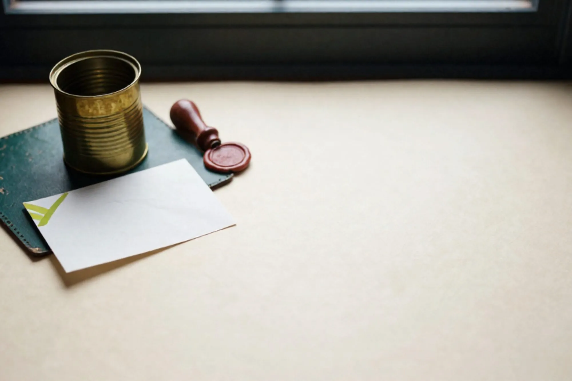 Brass pneumatic tube canister on green leather blotter, folded paper slip with ribbon, red wax seal, ivory paper surface.
