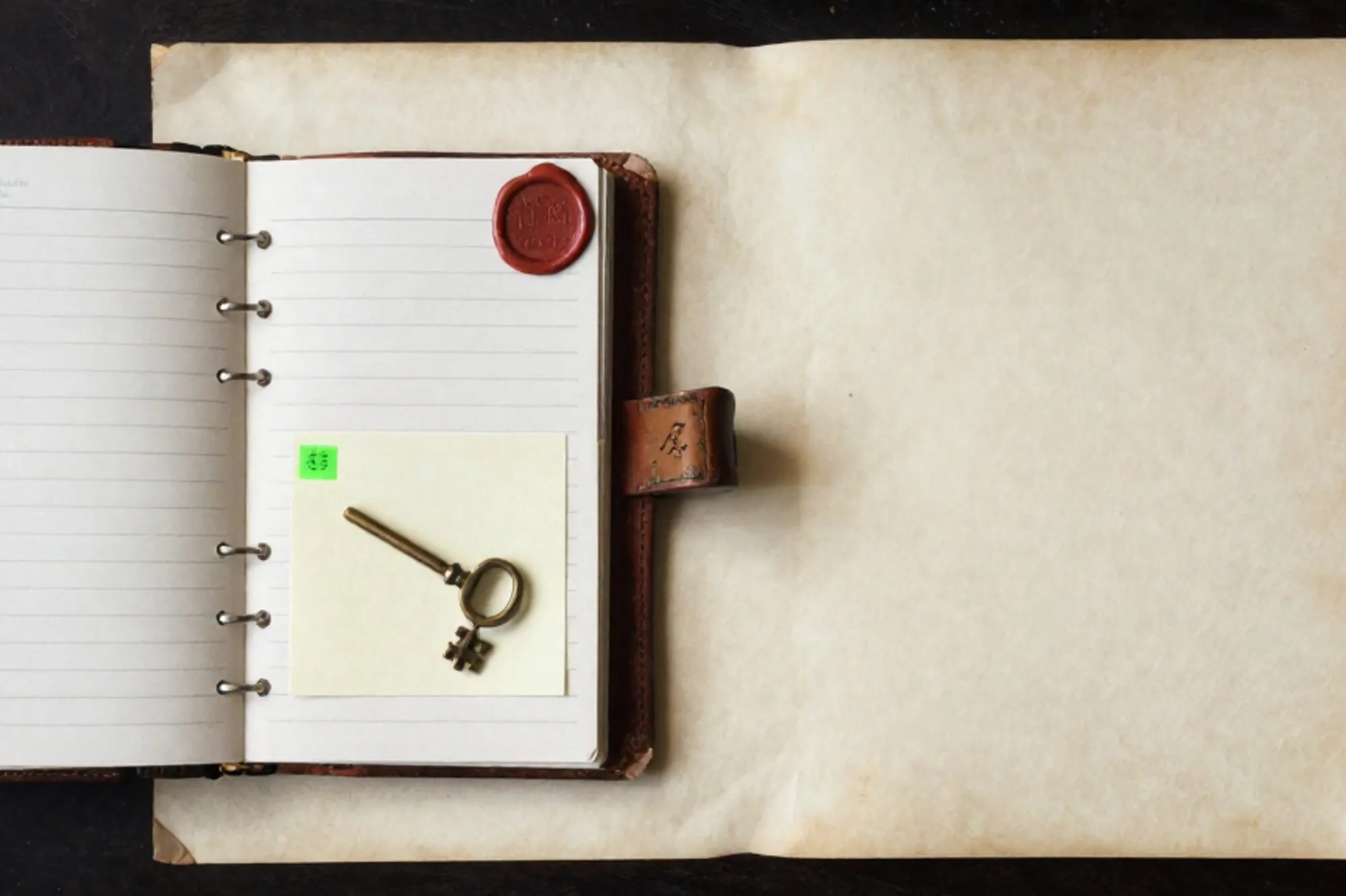 Open leren logboek met papieren tabs, groene plaknotitie, messing sleutel, ijzeren label, rood wax-zegel op ivoor.